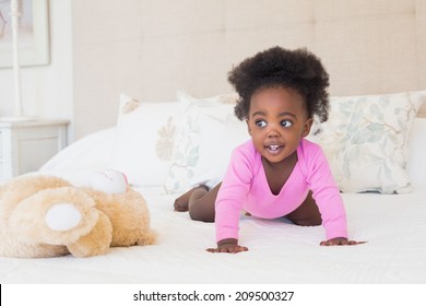 Baby Girl In Pink Babygro Crawling On Bed At Home In The Bedroom