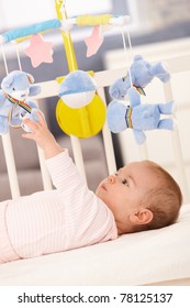 Baby Girl Playing In Bed With Mobile Toy Bear.?