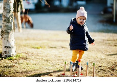 Baby girl playing a game throwing ring toss outdoor. - Shutterstock ID 2196214719