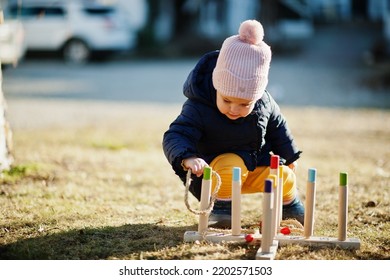 Baby girl playing a game throwing ring toss outdoor. - Shutterstock ID 2202571503