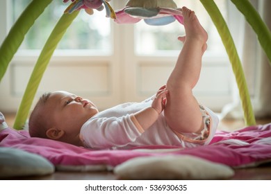 Baby Girl Playing With Mobile In The Cradle