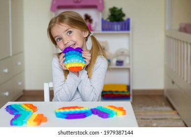 baby girl playing with rainbow pop it fidget. The Push bubble fidget touch toy is a washable and reusable silicone toy. Anti-stress toy for an autistic child. The concept of mental health popit toy