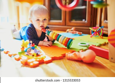 Baby girl playing with toys on the floor. Happy healthy little child at home