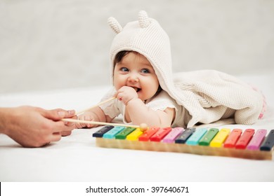 Baby girl playing with xylophone toy on blanket at home