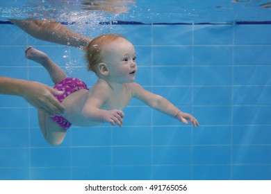 Baby Girl Pool Diving With Fun. Active Healthy Lifestyle, Sport Activity School, Classes, Lessons With Parents On Summer Family Vacation. Water Adjustment, Safety Skills, Breath Control For Toddlers