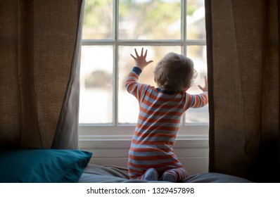 Baby Girl Pressing Her Face Against A Window Plane.