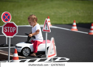 Baby girl in red pants and white shirt at toddler driving school - Powered by Shutterstock