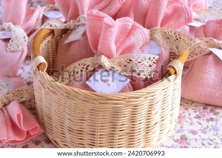 Baby girl shower favours pink jute gift bags with cotton lace and custom label text baby name, scented sachets in wicker basket baptism or first communion souvenirs, handmade original party presents
