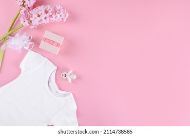 Baby girl shower mockup background, Flat lay composition layout with baby girl bodysuit, ceramic nipple or baby's dummy, gift box and confetti and hyacinth flowers with copy space on pink background