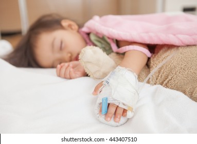 Baby Girl Sleeps On A Bed In Hospital With Saline Intravenous, Selected Focus.