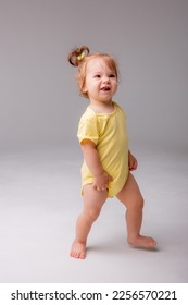 baby girl starting to walk takes her first steps on a white background - Shutterstock ID 2256570221