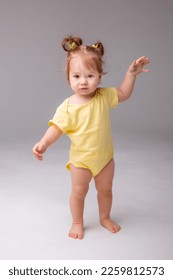 baby girl starting to walk takes her first steps on a white background - Shutterstock ID 2259812573