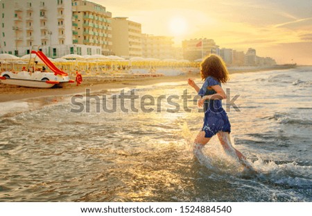 baby girl in a striped dress and runs to the sea the ocean