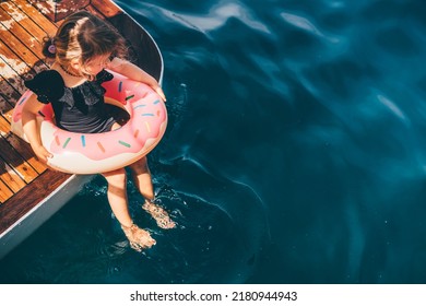 Baby Girl Swimming With Inflatable Ring In The Sea. 