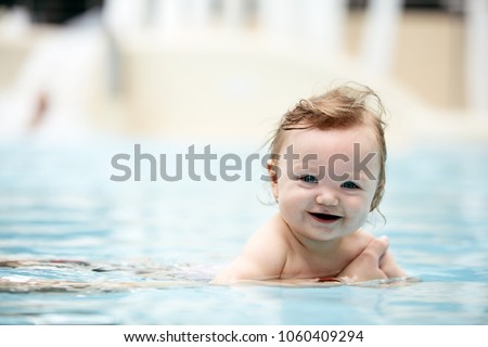 Baby girl swimming in a pool. Water park. Summer holiday activities.