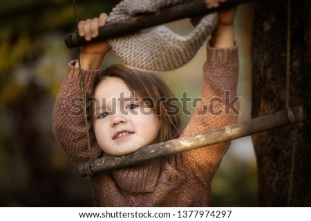 baby girl swinging on a wooden rope ladder near a tree, brown tone, hooligan and mischievous, and real childhood