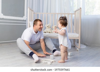 Baby Girl Takes Her First Steps, Dad Teaches Baby To Walk In The Nursery, Happy Fatherhood