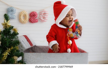 Baby Girl Toddler Sitting In A Large Gift Box White Background With Christmas Tree And Doll Cute Little Girl Dressed For Christmas Holiday Concept Celebrate With Family Happy New Year. Tim Christmas