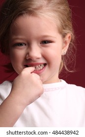 Baby girl touching her teeth. Close up. Red background
