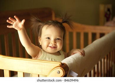 Baby Girl Waving Hand And Standing Up In Crib