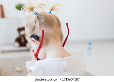 Baby Girl Wearing A Hearing Aid. Disabled Child, Disability And Deafness Concept.