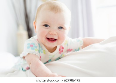A Baby girl in white bedding at home look nice