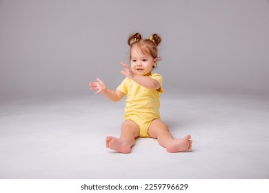baby girl with yellow bodysuit sitting on a white background - Shutterstock ID 2259796629