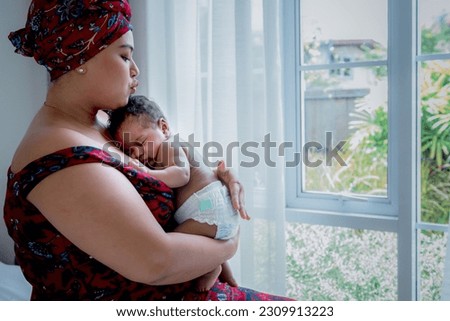 Baby half Nigerian half Thai, is 2-month-old baby newborn son, sleeping and happiness with his mother being held, to relationship family and infant newborn concept.