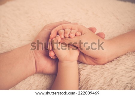 Baby hand. Closeup of baby hand into parents hands. Family concept. Baby holding mother's finger