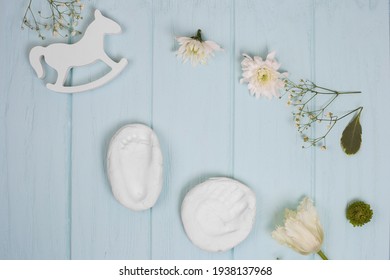 Baby Hand And Foot Print On Plaster On Blue Wooden Background, Flat Lay With Flower And Toy