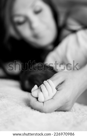 Similar – Baby schläft auf einer Decke mit der Hand ihrer Mutter.