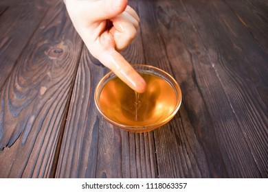 Baby Hand Holding A Finger In The Honey On Wooden Table