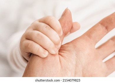 baby hand holds mom thumb. close up. Baby's grasp reflex. Parental care. Emotional bond between mother and son