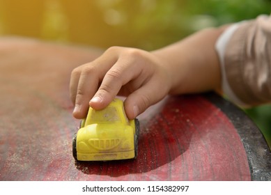 Baby Hand Playing With Old Toy Car On Table.