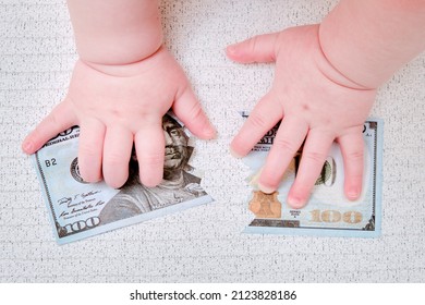 Baby hand and torn money in ?? dollars, close-up. Children fingers and an object on a white background