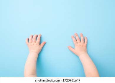 Baby hands on light blue table background. Pastel color. Closeup. Point of view shot.