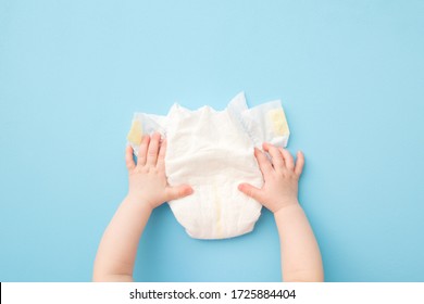 Baby Hands Touching White Diaper On Light Blue Table Background. Pastel Color. Closeup. Point Of View Shot.