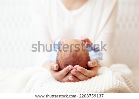 Baby Head in Mother Hands. Mum holding Newborn Boy lying on White Blanket. Infant Health Care and Development. Child Birth and Parents Love