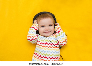 The Baby With Headphones On A Yellow Background