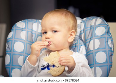 Baby In High Chair Eating Bread