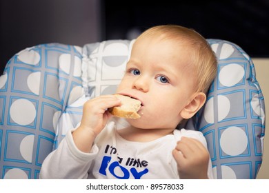 Baby In High Chair Eating Bread