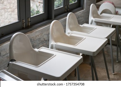 Baby High Chairs  In Restaurant. Empty White Plastic Chairs.