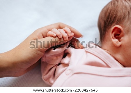 The baby holds his mother's finger in his hand. Family concept. Mom and baby. 