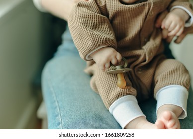 Baby Holds A Pacifier In His Mother Arms