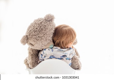 Baby Hugs A Big Teddy Bear On A White Background