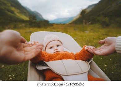 Baby infant in bouncer outdoor family travel lifestyle mother and father holding child hands summer vacations together                  - Powered by Shutterstock