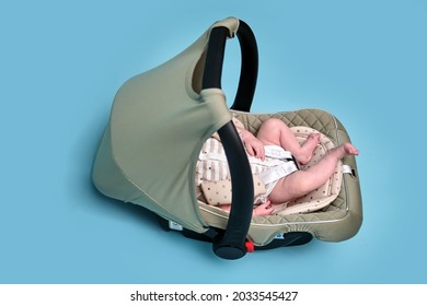 Baby In Infant Car Seat On Blue Studio Background. Carrier For Transporting Newborn Babies In A Chair