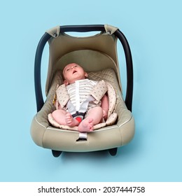 Baby In Infant Car Seat On Blue Studio Background. Carrier For Transporting Newborn Babies In A Chair