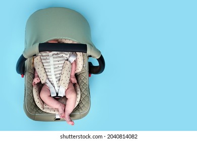 Baby In Infant Car Seat On Blue Studio Background. Carrier For Transporting Newborn Babies In A Chair