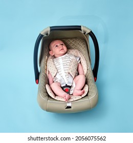 Baby In Infant Car Seat On Blue Studio Background. Carrier For Transporting Newborn Babies In A Chair